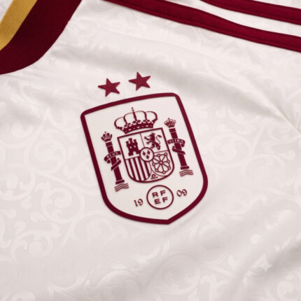 Detalle del escudo bordado con dos estrellas en la camiseta visitante de España 2026. Segunda equipación oficial de la selección.
