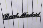 Camiseta estilo béisbol del Real Madrid, diseño blanco con rayas y detalles en negro y verde lima, con el escudo del club. — foto 2