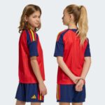 Primera equipación de niño de España para la Final del Mundial 2026. Conjunto de camiseta y pantalón rojos oficiales.