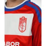 Primera equipación del Granada CF para niños temporada 2026-27. Conjunto de camiseta y pantalón oficial para los más pequeños.